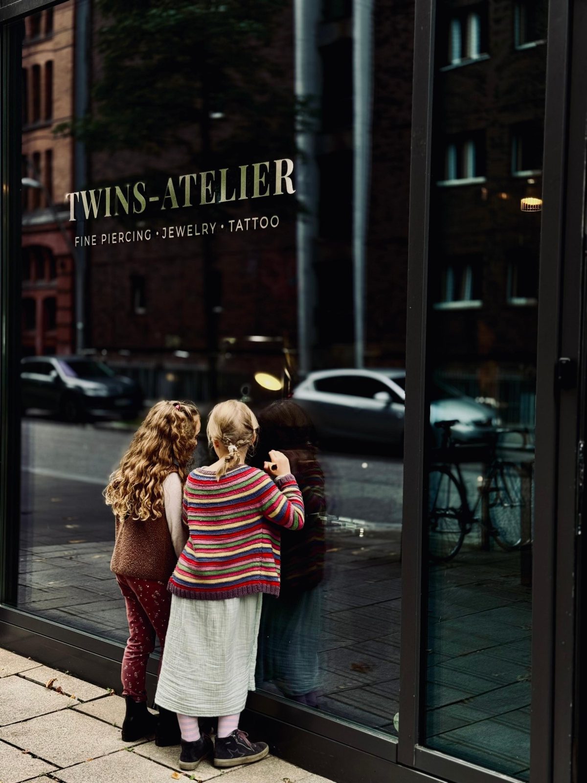 Zwei Mädchen schauen gespannt in das Schaufenster des TWINS-ATELIER