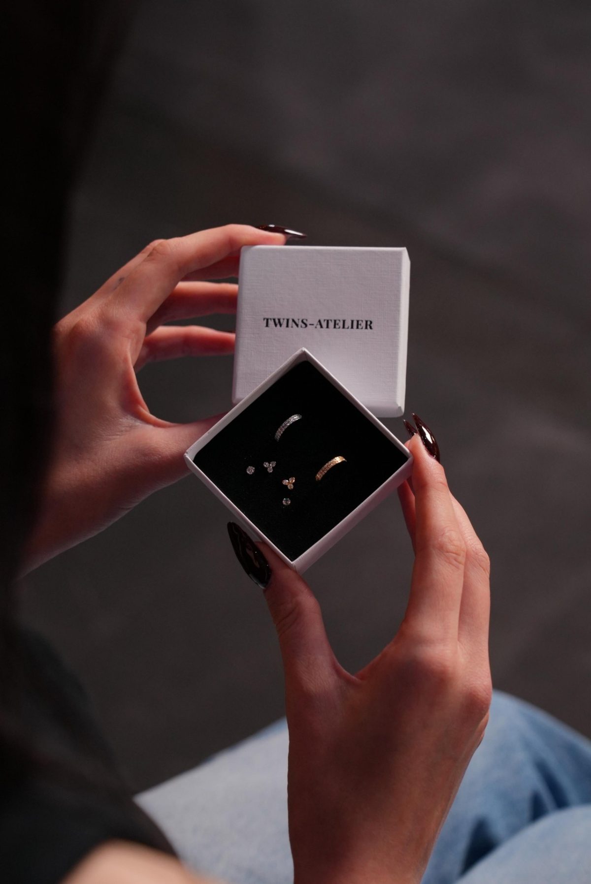 Hände halten eine TWINS-ATELIER Schmuckbox mit feinen Ohrringen